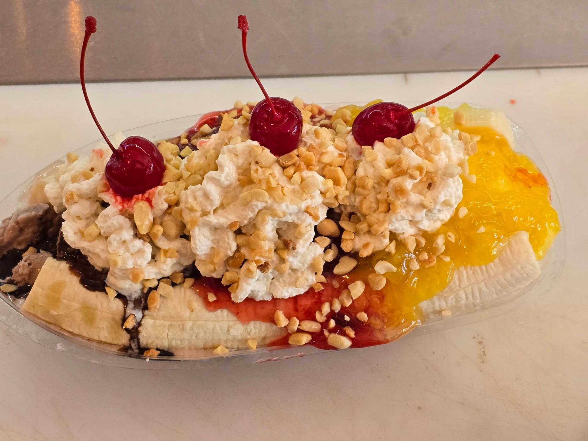Banana split with three cherries, whipped cream, pineapple, and strawberry toppings