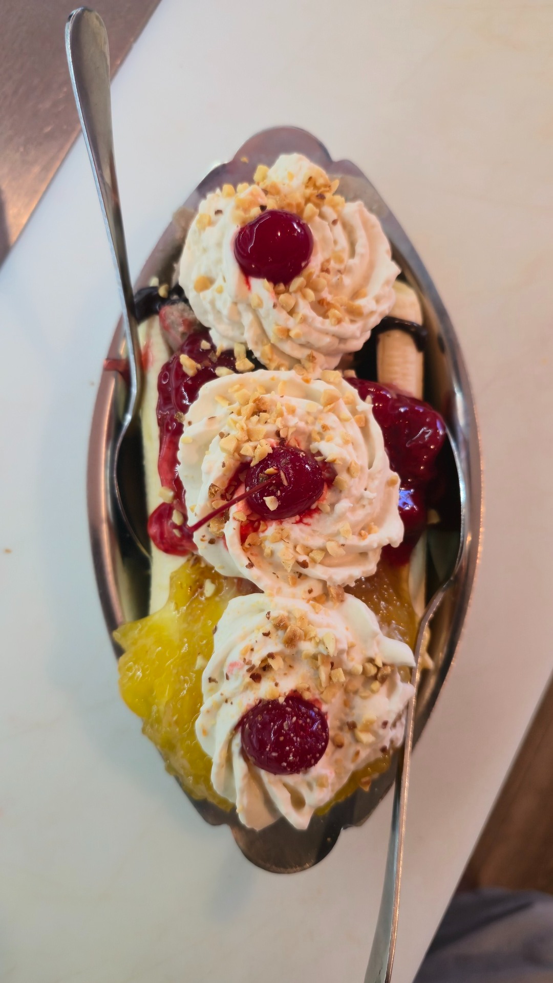 Banana split served in a retro silver boat dish with whipped cream rosettes and maraschino cherries